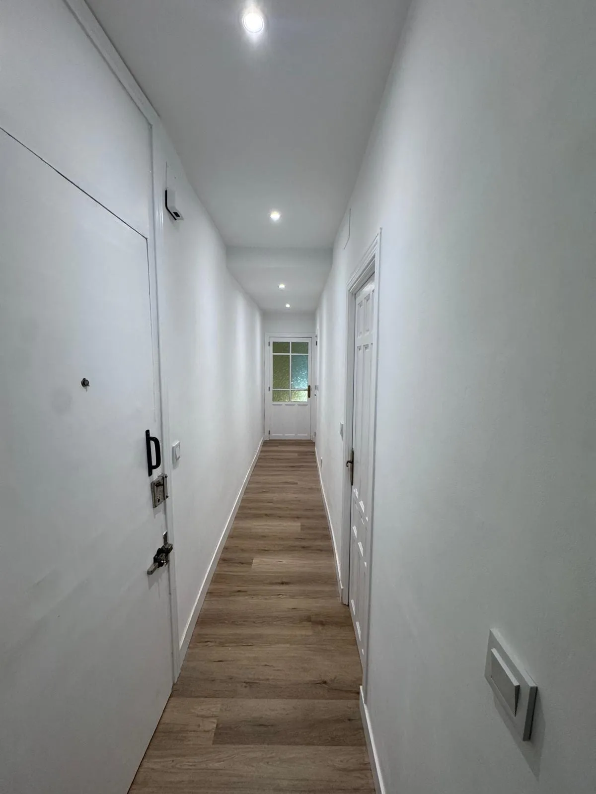 Pasillo reformado con suelo vinílico de madera y luces empotradas